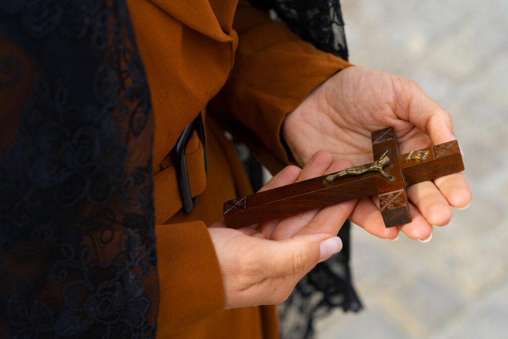 mujer devota sujeta una cruz con la imagen de Cristo mientras hace una peregrinación a Caravaca
